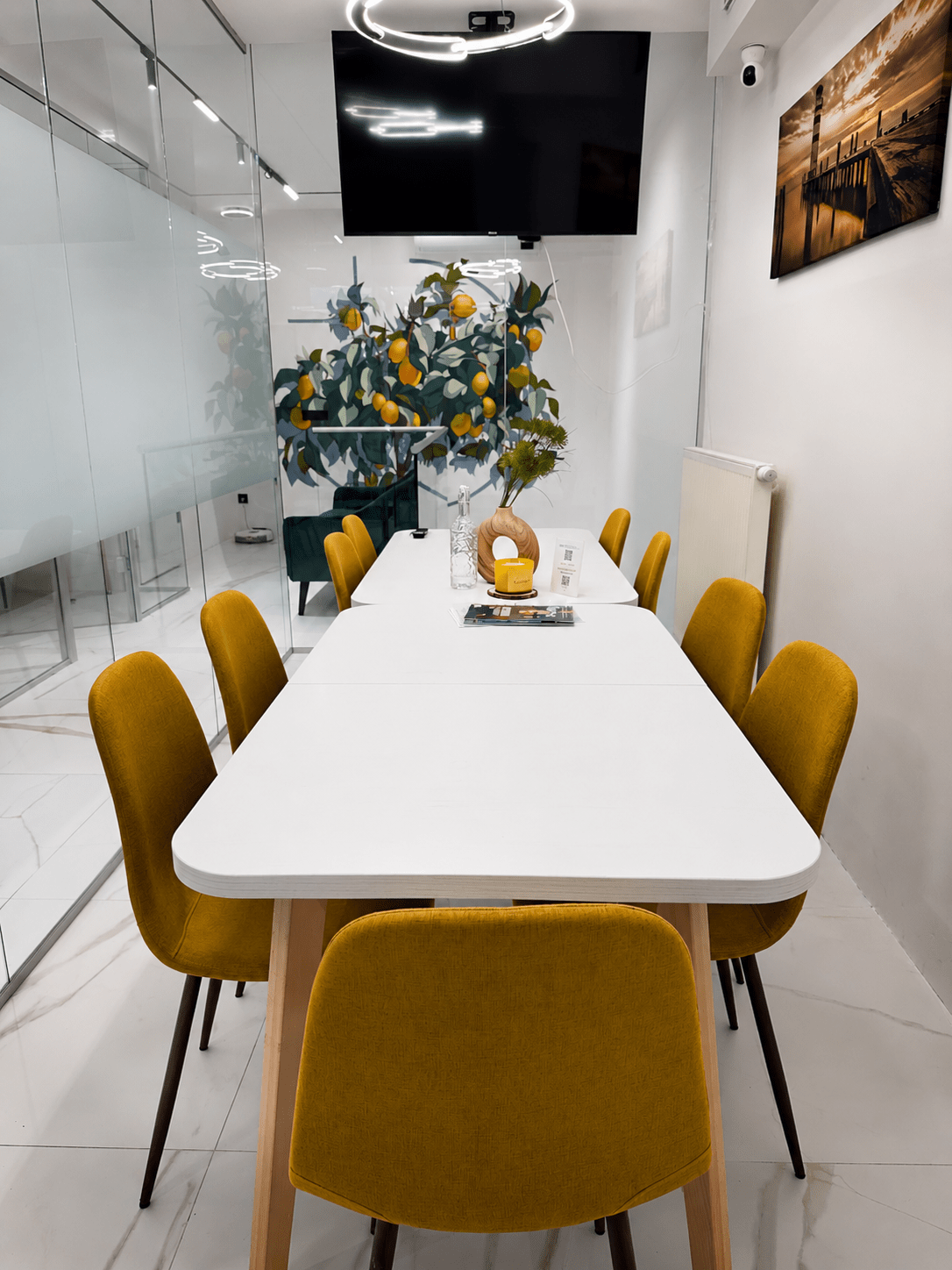 Svetlá moderná zasadačka s bielym stolom, žltými stoličkami, presklenými stenami a minimalistickým interiérom v LEMON OFFICE.